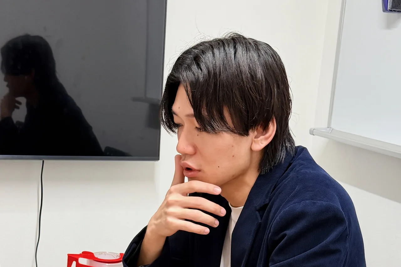 口元に手を当てて話を聞く杉山